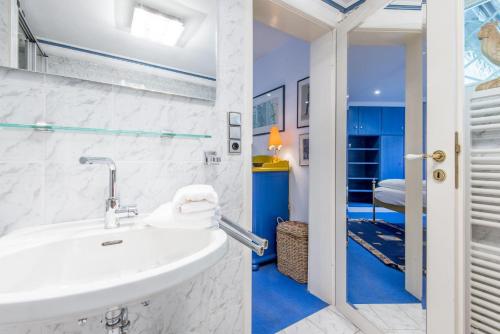 a white bathroom with a sink and a bedroom at Haus Hideaway in Westerland (Sylt)