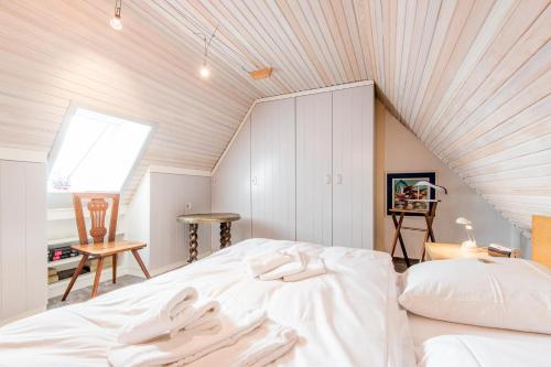 a attic bedroom with a white bed and a window at Haus Neptun Whg 6 in Munkmarsch