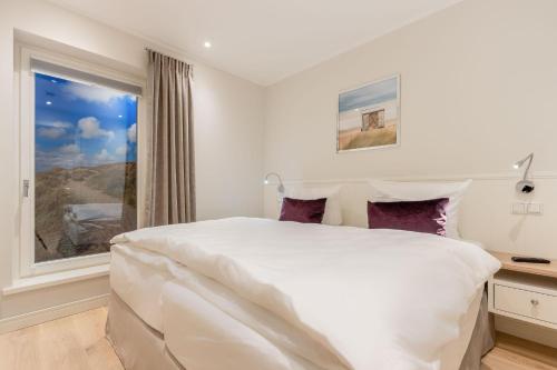 ein weißes Schlafzimmer mit einem großen Bett und einem Fenster in der Unterkunft Süster Hüs in Westerland