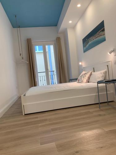 1 dormitorio con 1 cama blanca grande y 2 ventanas en Sa Conca, en Cagliari