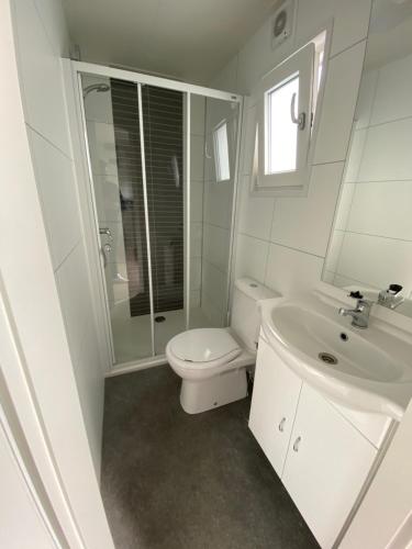 een witte badkamer met een toilet en een wastafel bij Luxe Chalet Marbella IJmuiden aan Zee in IJmuiden