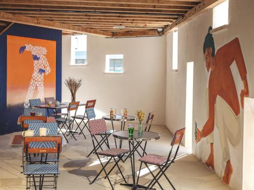 a room with tables and chairs and a painting on the wall at Eklo Marne La Vallée in Serris