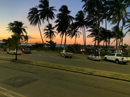 a street with cars driving down a street with palm trees at Temporada Litorânea slz in São Luís