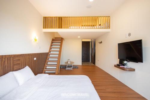 a bedroom with a bed and a tv and a staircase at 我們這一家輕旅宿 in Xiaoliuqiu