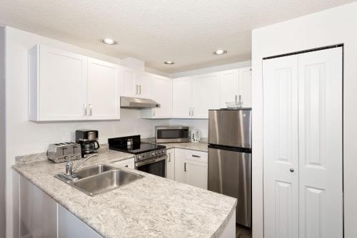 a kitchen with white cabinets and a stainless steel sink at Lake Placid Lodge by Whiski Jack in Whistler