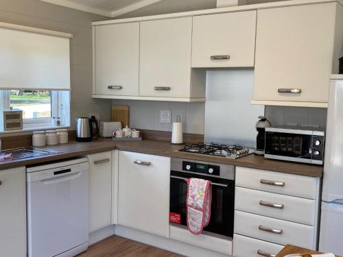 a kitchen with white cabinets and a stove top oven at Hollicarrs - Newlands in York