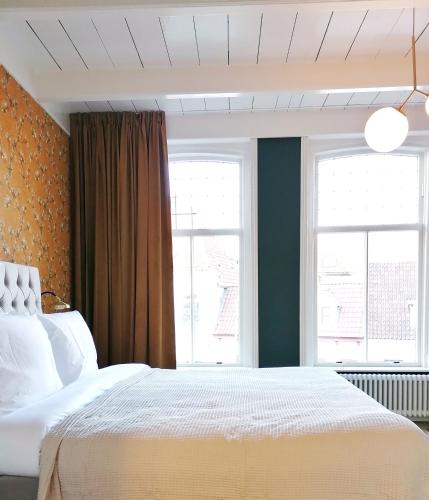 een slaapkamer met een wit bed en 2 ramen bij B&B De Stadssingel in Steenwijk