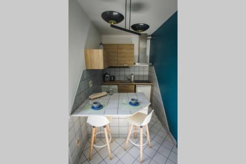 a small kitchen with a table and two stools at Marin Malouin,à 2 pas de la mer & d'intra muros, proche gare. in Saint Malo