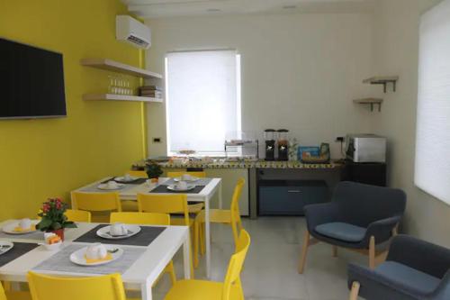 eine Küche mit 2 Tischen und gelben Stühlen in einem Zimmer in der Unterkunft B&B CaselloA Suites in Syrakus