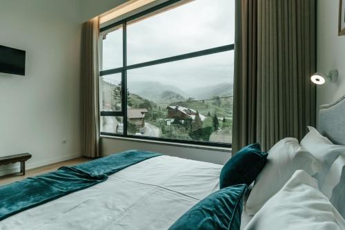 a bed in a room with a large window at Unhais Valley - Country House in Unhais da Serra
