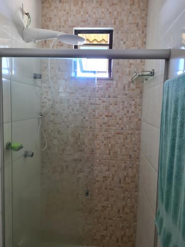 a shower with a glass door and a window at Lindo Village na Praia de Stellamaris in Salvador