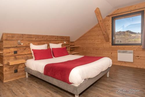 a bedroom with a large bed with red pillows at Gîtes de Moyenmont in La Bresse