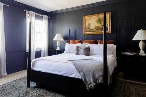 a bedroom with a large bed with blue walls at The Litchfield Inn in Litchfield