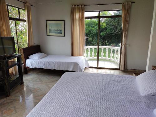 1 dormitorio con 2 camas y ventana con balcón en Costa del Llano Hotel Campestre, en Villavicencio