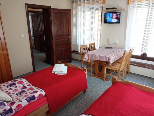 a room with two beds and a table and a television at Dom Natury in Karpacz