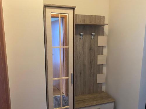 a wooden closet with a glass door in a room at Thermal apartman in Hajdúszoboszló