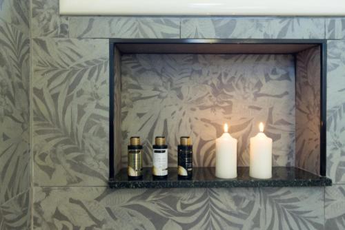 a shelf with three bottles and candles on it at °° VILLA ANNA°° in Villasimius