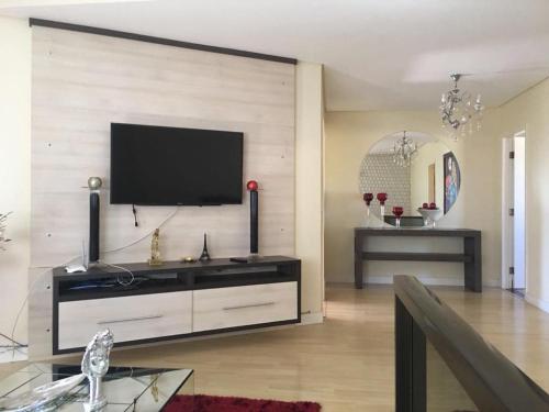 een woonkamer met een flatscreen-tv aan de muur bij Sobrado com 5 suítes para temporada e show rural in Cascavel