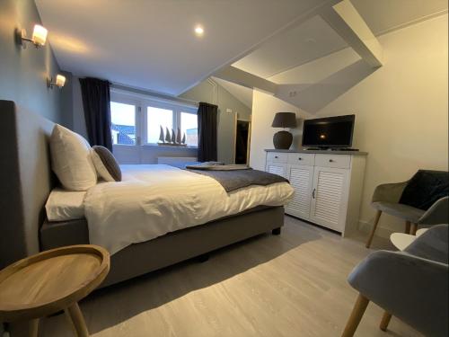um quarto com uma cama, uma televisão e uma cadeira em B&B de Keinsmer em 't Zand