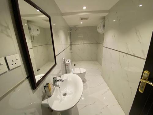 a white bathroom with a sink and a mirror at فيجن للشقق المخدومة ــ اقتصادي in Buraydah