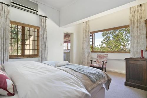 a bedroom with a large bed and two windows at Waterfall Farm Self-Catering Cottages Citrusdal in Citrusdal