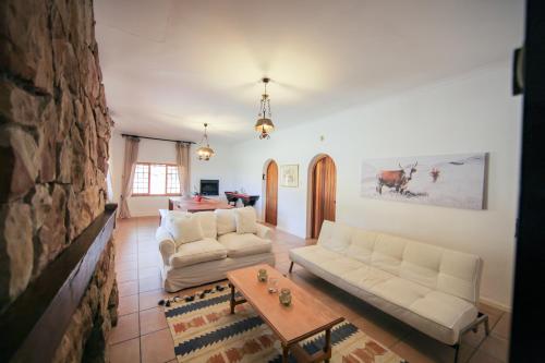 a living room with two white couches and a table at Waterfall Farm Self-Catering Cottages Citrusdal in Citrusdal