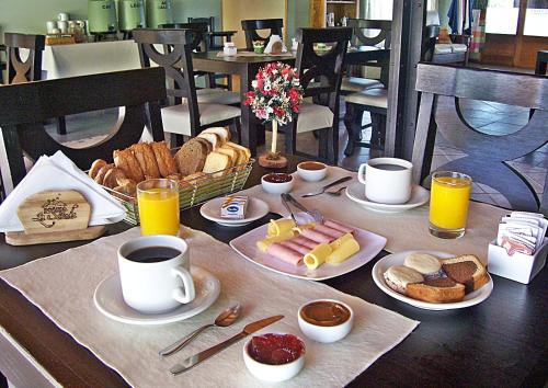 a table with breakfast foods and cups of coffee at Posada La Soñada in Villa General Belgrano