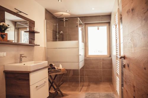 a bathroom with a sink and a glass shower at Appartement Pointschneiderhof in Maishofen