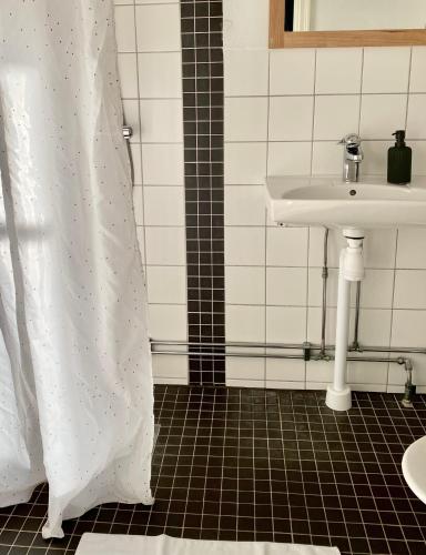 a bathroom with a white shower curtain and a sink at Kaptenshuset Hotell in Kivik