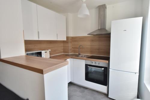 a kitchen with white cabinets and a sink and a refrigerator at Welcome Home in Linas