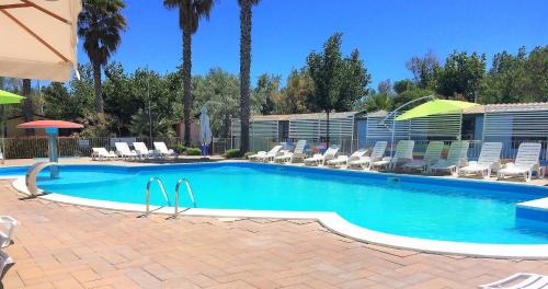 a swimming pool with chairs and umbrellas in a resort at JuliaMare Village in Giulianova