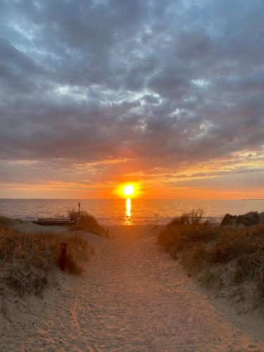 a sunset over the ocean with a sandy beach at Mellbystrand Björkvägen Apartment in Mellbystrand