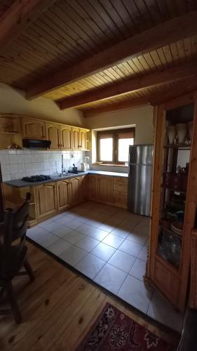 uma cozinha com armários de madeira e um frigorífico de aço inoxidável em Dom nad jeziorem em Gostynin