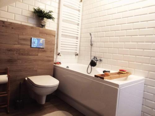 a bathroom with a white tub and a toilet and a sink at Pokoje goscinne u Olguni in Chyrowa