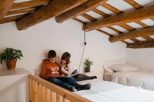 two people sitting on a bed reading books at Ca lEspavil in Cardedeu