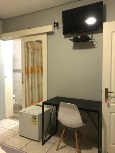a desk with a chair and a television on a wall at Homey Guesthouse in Gaborone