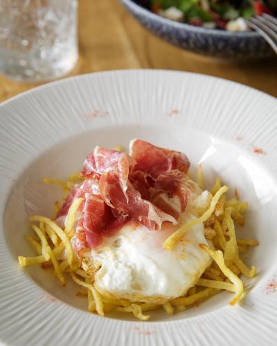 a plate of food with bacon and fries on a table at Nuria in Tarragona