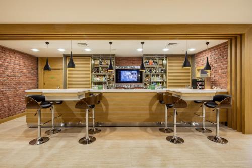 a bar with stools and a tv in a room at Holiday Inn Antalya - Lara by IHG in Antalya