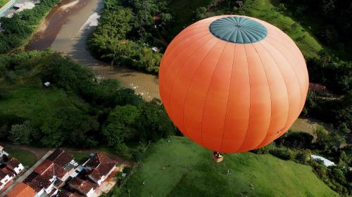 an orange hot air balloon flying over a field at Hotel Cacique Chalalá in Charalá