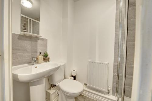 a white bathroom with a toilet and a sink at 2-BR Apartment, En-suite, Allocated Parking, next to Playground in Coventry