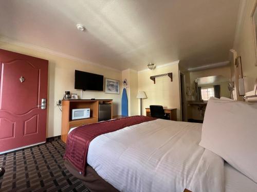 a hotel room with a bed and a red door at Riverside Inn & Suites Santa Cruz in Santa Cruz