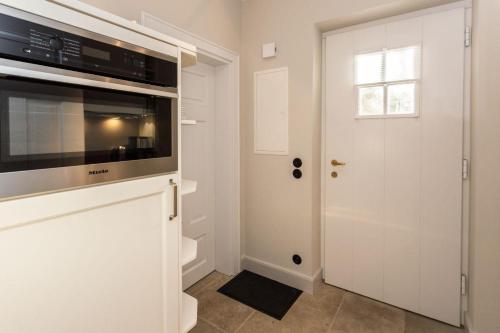 une cuisine blanche avec un four micro-ondes et une porte dans l'établissement Villa Maybach Whg 2 Else, à Westerland