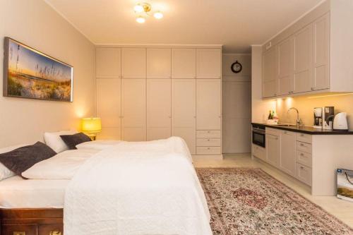 1 Schlafzimmer mit einem weißen Bett und einer Küche in der Unterkunft Villa Maybach Whg 3 in Westerland