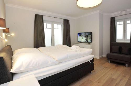 ein Schlafzimmer mit einem großen weißen Bett und einem Stuhl in der Unterkunft Haus Doktor Ross Strasse 31 Whg 4 in Westerland