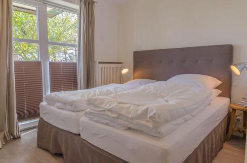 ein großes Bett in einem Schlafzimmer mit einem großen Fenster in der Unterkunft Haus Hauke Whg 1 in Westerland