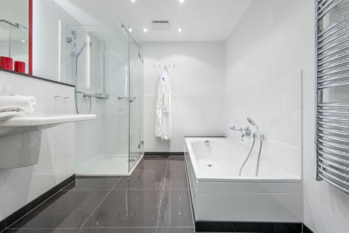 La salle de bains blanche est pourvue d'une baignoire et d'un lavabo. dans l'établissement Art your Life Haus Schützenstrasse Whg 2, à Westerland