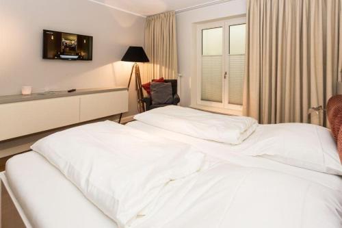 2 weiße Betten in einem Hotelzimmer mit Fenster in der Unterkunft Die Villa 1903 Whg 4 in Westerland
