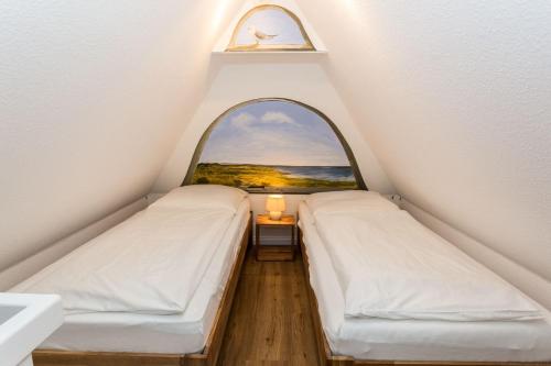 two beds in a room with an arch window at Haus Heefkant Whg 10 in Rantum