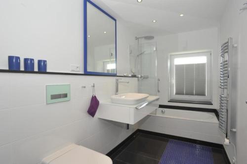 ein Bad mit einem Waschbecken, einem WC und einem Fenster in der Unterkunft Haus Schuetzenstrasse Whg 4 in Westerland