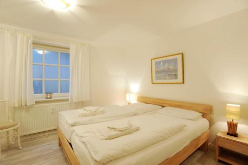 Un dormitorio blanco con una cama grande y una ventana. en Haus Heefkant Whg 5, en Rantum
